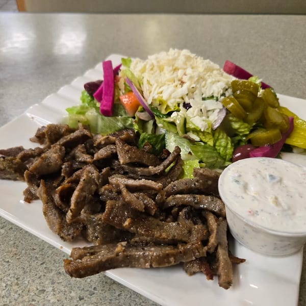 LaVie Mediterranean Grill's gyro plate with sliced meat, salad, feta, pickles, and tzatziki sauce.