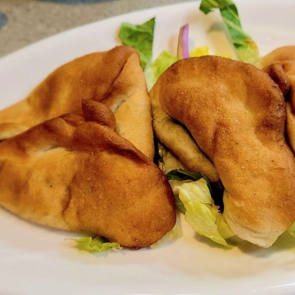 Golden-brown LaVie Mediterranean Grill fatayer pastries with fresh green lettuce on a white plate.