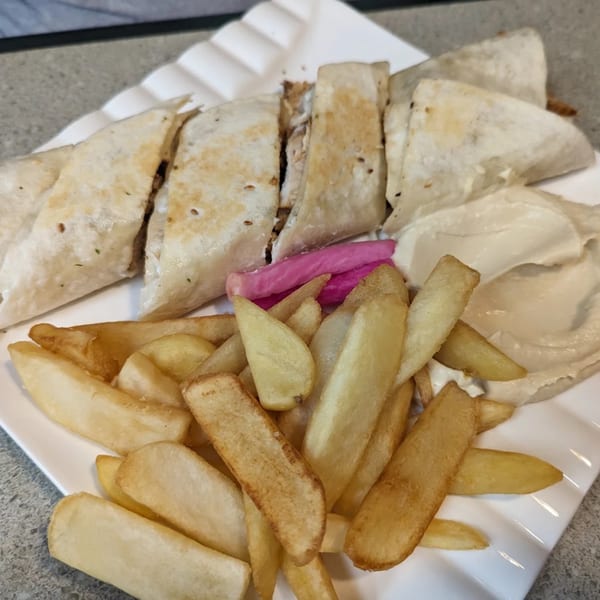 LaVie Mediterranean Grill's shawarma wraps, hummus, pickled turnips, and french fries on a white plate.